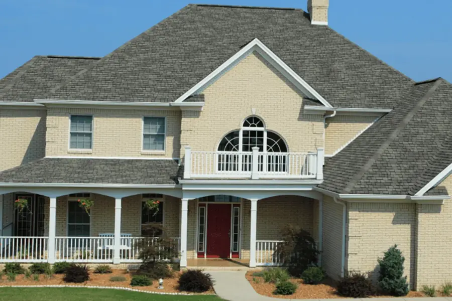 Two-story brick home with freshly painted white trim, porch columns, and railings